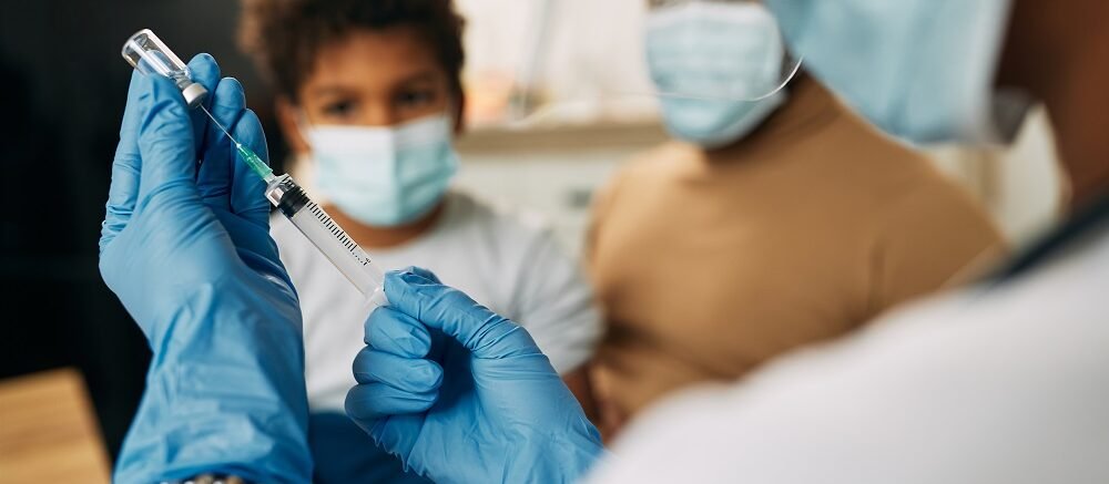 "Healthcare workers in gloves and masks preparing syringe for vaccination in clinical setting"