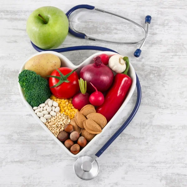 "Heart-shaped bowl with healthy foods, apple and stethoscope promoting heart health and balanced diet"