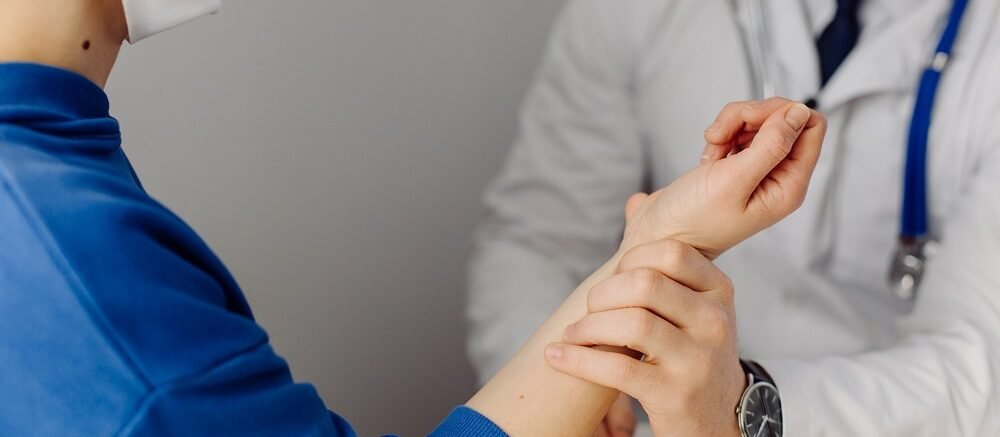 "Doctor checking patient pulse by hand during clinical examination at Infinity Heart Hospital Jabalpur"