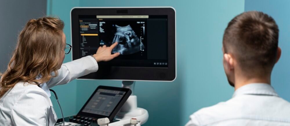 "Doctor reviewing pregnancy ultrasound results with expectant father at Infinity Heart Hospital Jabalpur"