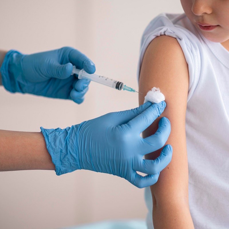 "Child receiving vaccination in arm from gloved healthcare professional"