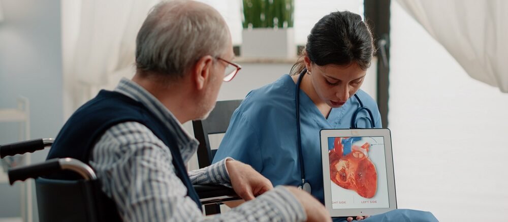 "Doctor educating elderly patient on heart anatomy with tablet at Infinity Heart Hospital Jabalpur"