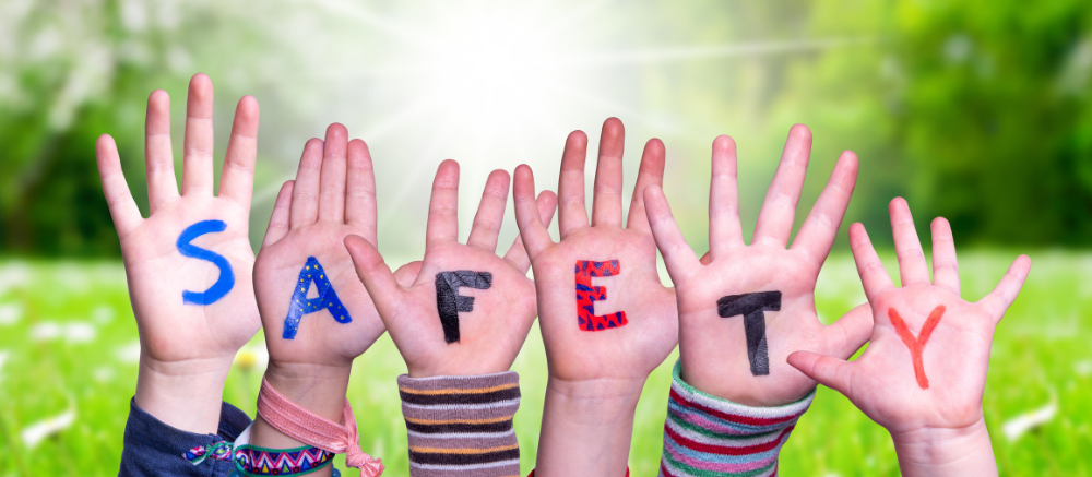 "Children’s hands with letters spelling SAFETY outdoors"